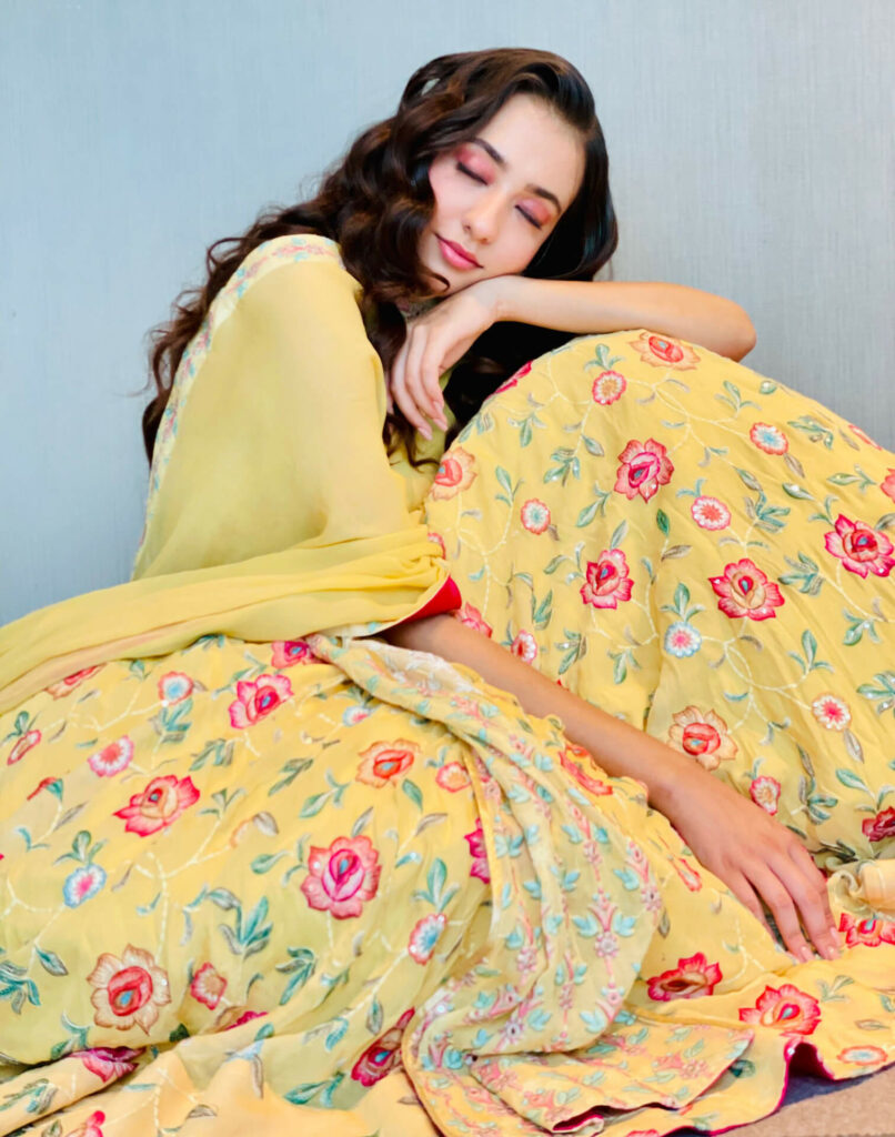 Nikeet dazzles in a yellow-magenta floral suit with bold eye makeup.
